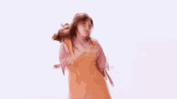 a woman in a pink shirt and orange dress is dancing .