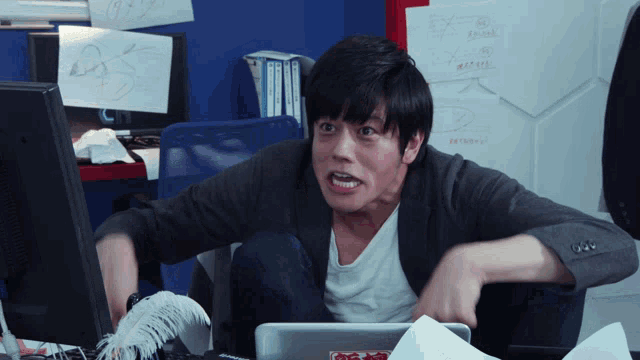 a man sitting in front of a computer with a sticker on his laptop that says ' ao '