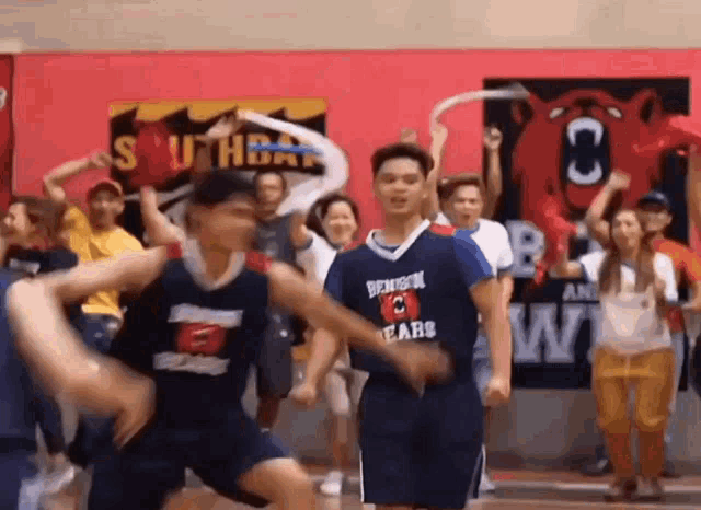 a group of basketball players are dancing on a court while a crowd watches .