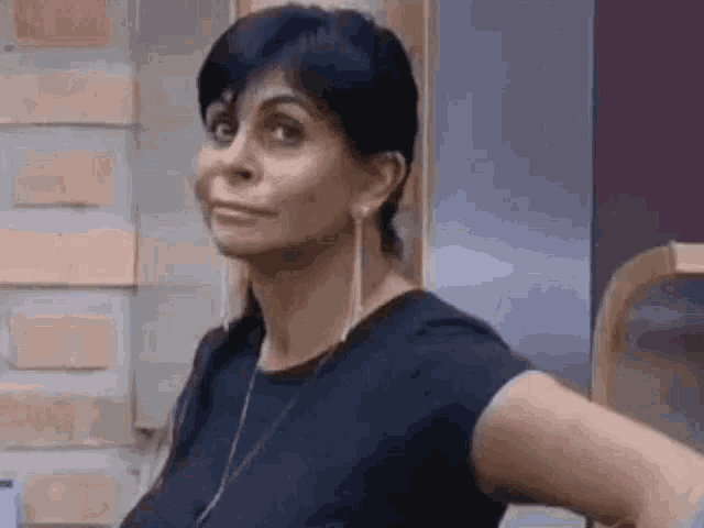 a woman in a black shirt is making a funny face while standing with her hands on her hips .