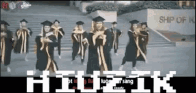 a group of graduates are dancing in front of a sign that says ship of k.