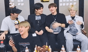 a group of young men are sitting on a couch laughing and holding balloons .