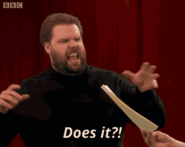 a man with a beard is holding a piece of paper and says does it
