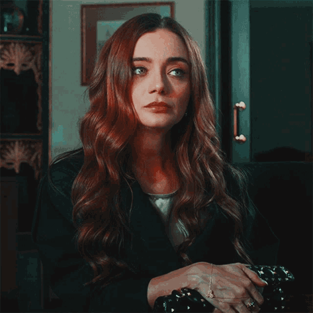 a woman with long red hair and a black jacket