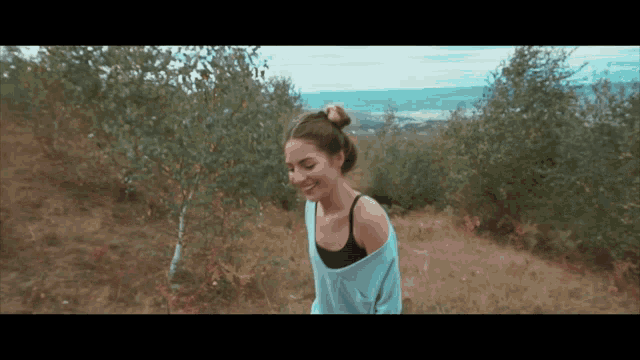 a woman in a blue sweater is walking through a grassy field