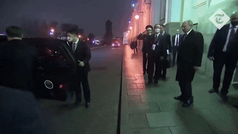 a group of men in suits and ties are walking down a sidewalk in front of a building with a sign that says t.