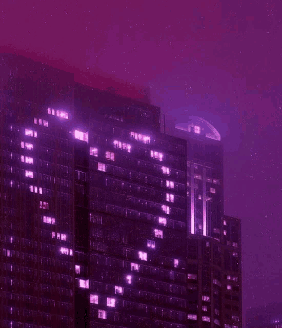 a building with a purple sky in the background has a lot of windows lit up at night