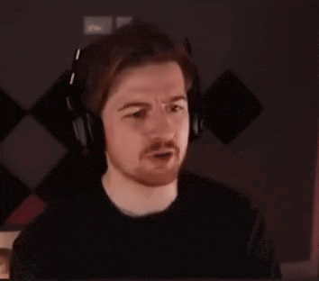 a man with a beard wearing headphones is sitting in front of a computer screen .