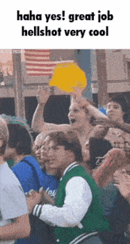 a man in a green jacket is holding a yellow hat in front of a crowd of people