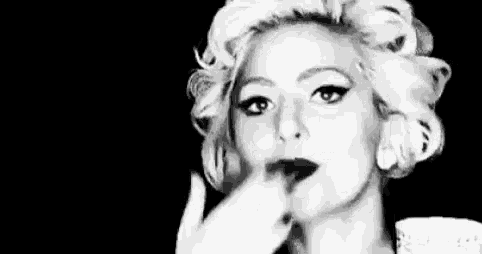 a black and white photo of a woman with curlers in her hair and lipstick on her lips .