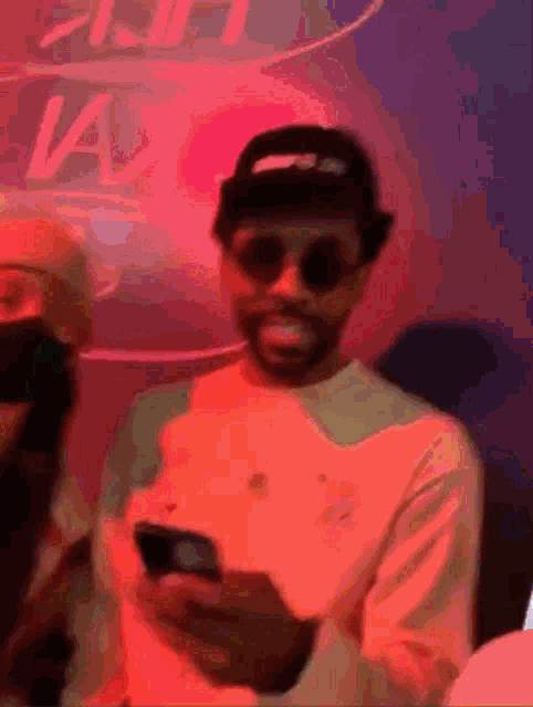 a man wearing sunglasses and a hat looks at his phone