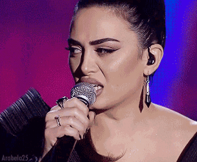 a woman singing into a microphone with arabela25 on the bottom right
