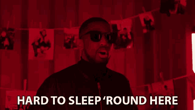 a man wearing sunglasses says hard to sleep round here in a red room