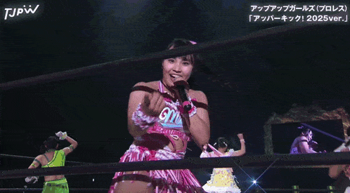 a woman singing into a microphone with the letters tjpw on the bottom right