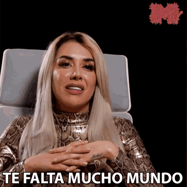a woman is sitting in a chair with the words te falta mucho mundo behind her