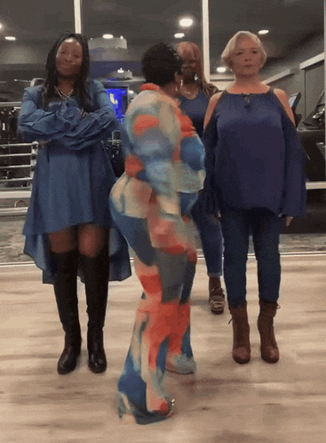 a woman in a blue dress is hugging another woman in an orange and blue outfit