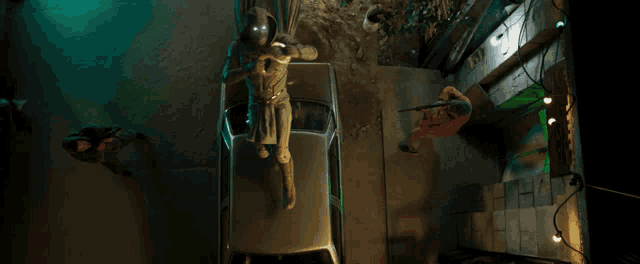 an aerial view of a man in a superhero costume standing on top of a car
