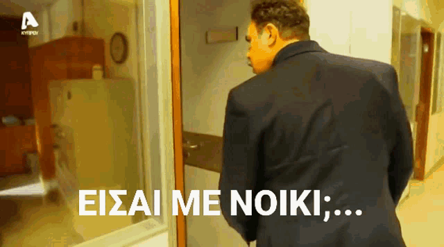 a man in a suit is standing in front of a door that says eisai me noiki on it