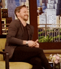 a man in a suit sits in a chair with his legs crossed