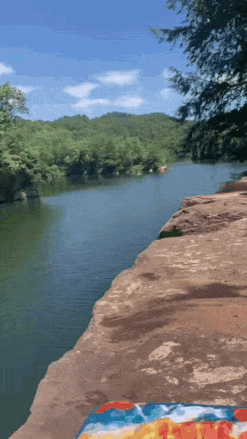 a cliff overlooking a lake with a towel on the ground