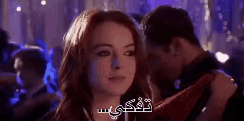 a man is whispering into a woman 's ear while she looks at him .
