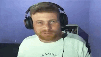 a man with a beard wearing headphones and a microphone is looking at the camera .
