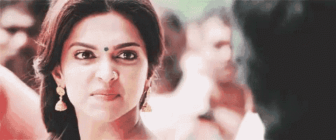 a close up of a woman 's face with a bindi on her forehead and earrings .