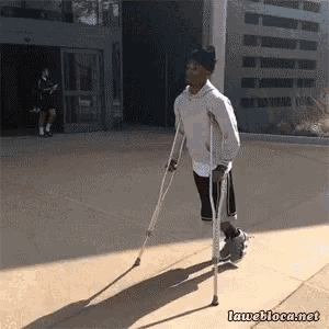 a man with crutches is walking on a sidewalk in front of a building