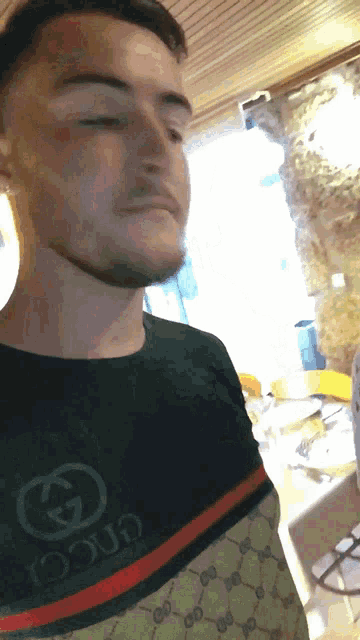 a man wearing a gucci shirt with a red and green stripe