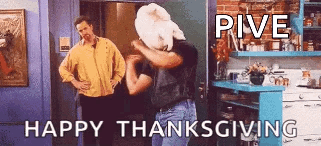 two men are standing in a kitchen and one of them is holding a turkey over his head .