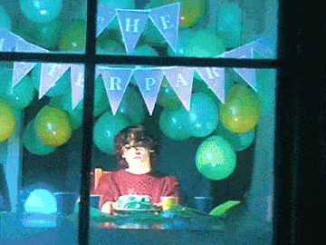 a woman sits at a table with a cake under a banner that says " the r.p.a.k. "