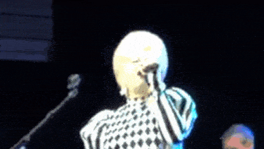 a woman is singing into a microphone in a dark room