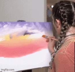 a woman is painting a sunset on a canvas with a brush ..