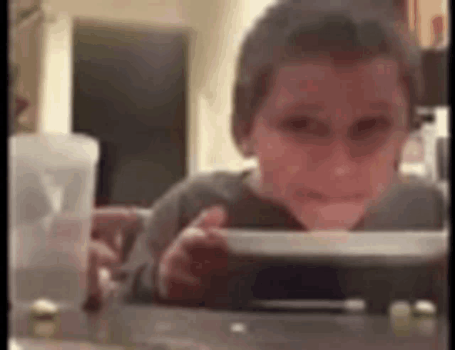 a young boy is sitting at a table playing a video game on a tablet .