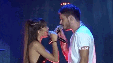 a man and woman singing into microphones on a stage .