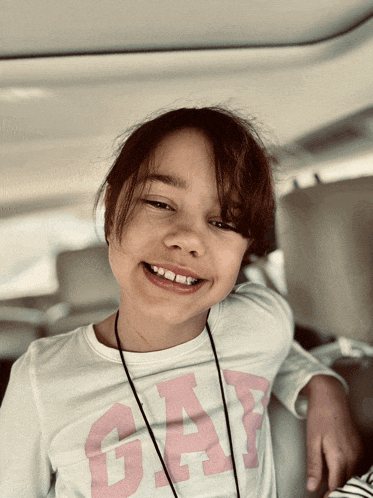 a little girl wearing a white gap shirt smiles for the camera
