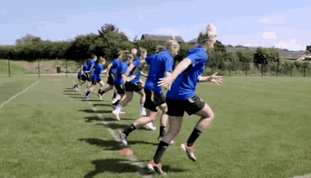 a group of female soccer players in blue shirts are running on a field