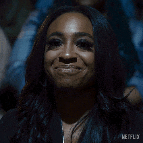 a woman is smiling in a dark room with a netflix logo in the corner