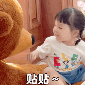 a little girl is sitting next to a teddy bear wearing a disney shirt