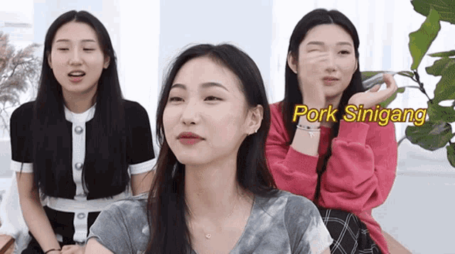a group of young women are sitting in front of a sign that says pork sinigang