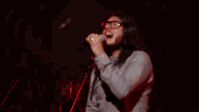 a man singing into a microphone in a dark room
