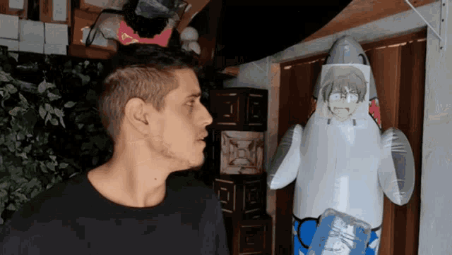 a man standing next to an inflatable shark that has a face on it