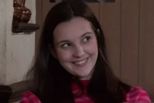 a young woman is smiling and looking at the camera while wearing a pink and white striped shirt .