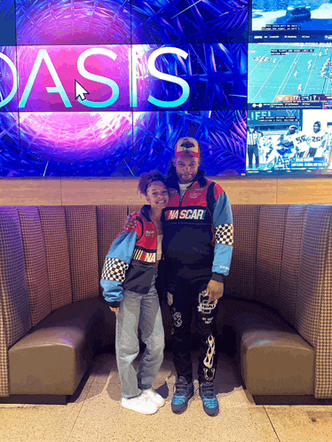 a man in a nascar jacket stands with a woman