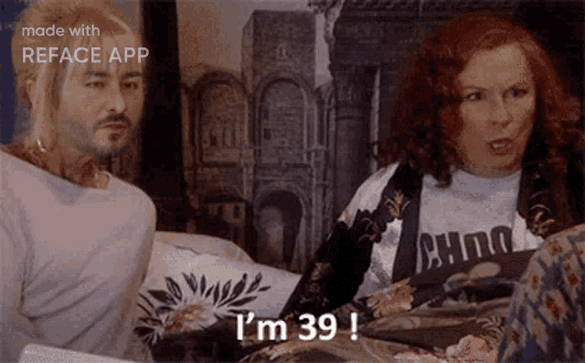 a man and a woman are sitting on a bed and the woman is saying i 'm 39 !