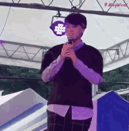 a man is holding a microphone in front of a sign that says # mayward