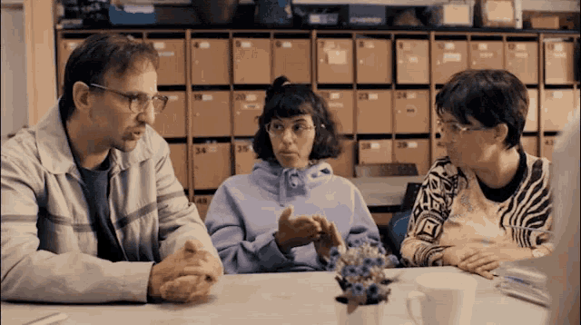 a woman in a purple sweatshirt sits at a table with two other women