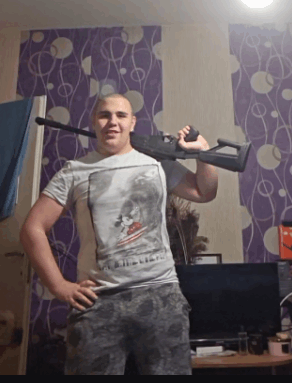 a man holding a gun in front of a wall with purple circles