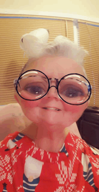 a woman wearing glasses and a red sweater is making a face