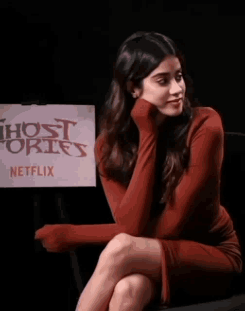 a woman in a red dress sits in front of a sign that says ghost stories on it
